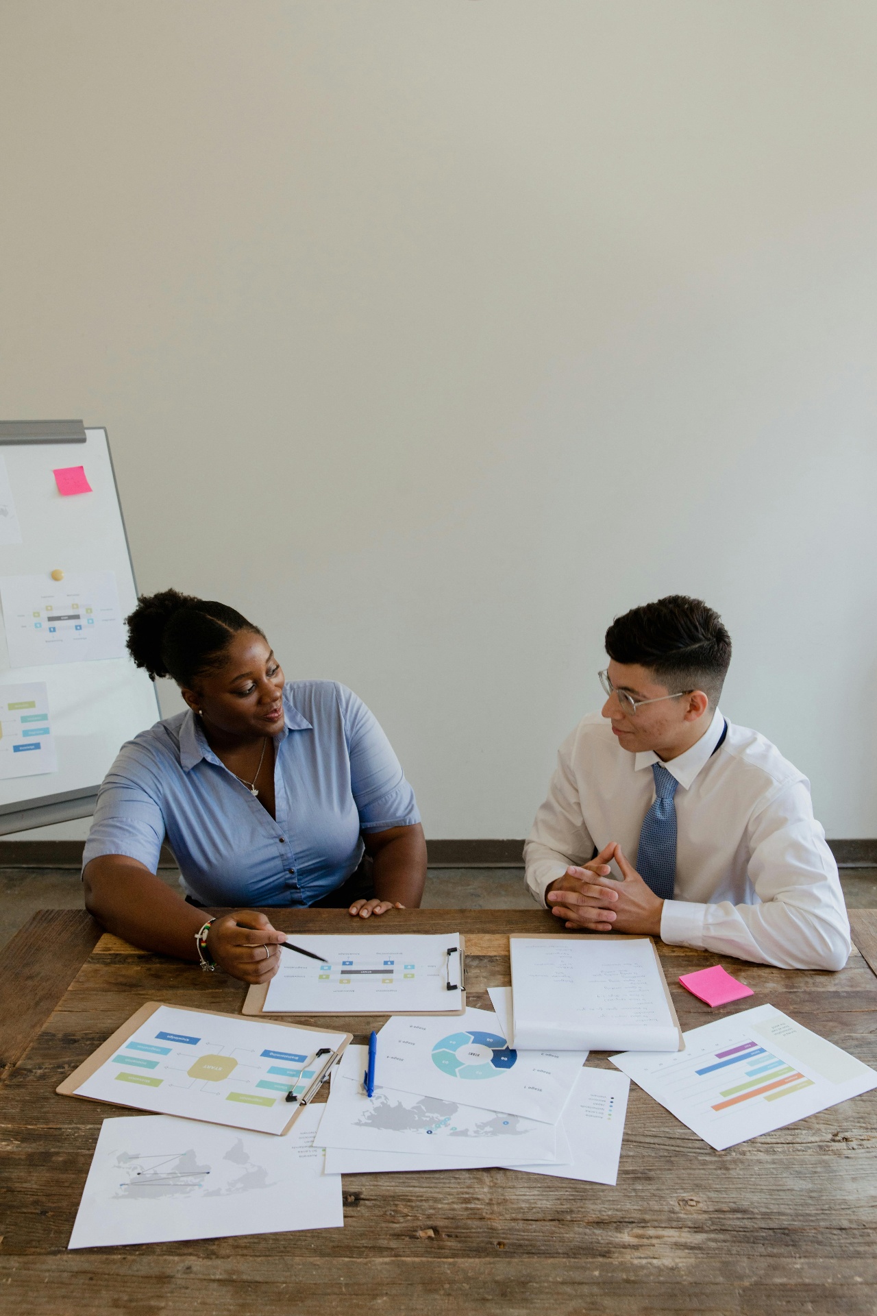 Two consultants reviewing business strategy documents and workflow diagrams together at a wooden table