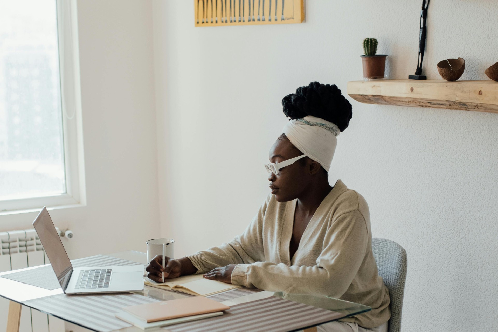 Founder of WorkWell Co. writing in a notebook beside a laptop in a calm, sunlit workspace